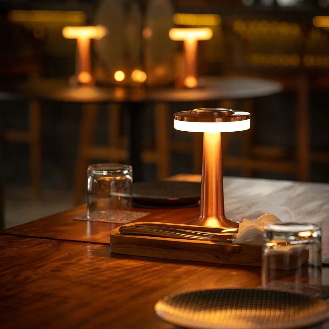 Moderne Tischlampe aus Kupfer auf Holztisch in gemütlichem Restaurantambiente.