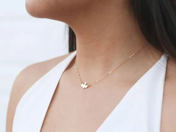 Frau mit goldener Halskette, Schmetterlingsanhänger, elegantes Schmuckdesign, Nahaufnahme.