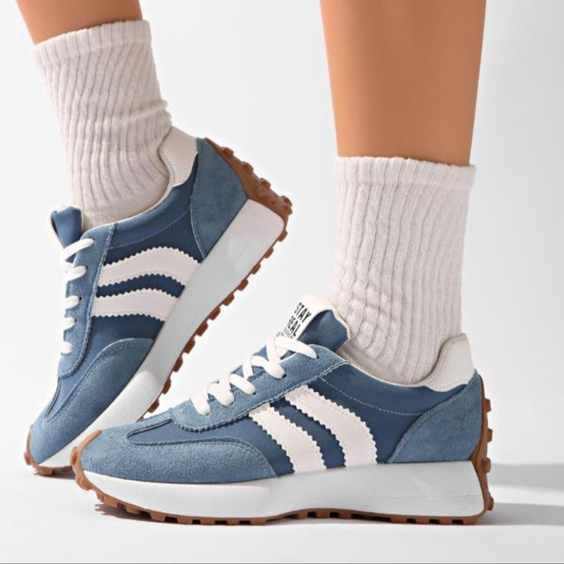 Blaue Sneaker mit weißen Streifen, getragen zu weißen Rippensocken, Seitenansicht mit angehobenem Fuß 8