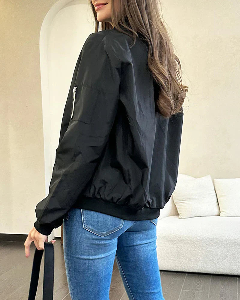 Frau in schwarzer Bomberjacke und blauer Jeans, modisch, lässig, urbaner Stil.