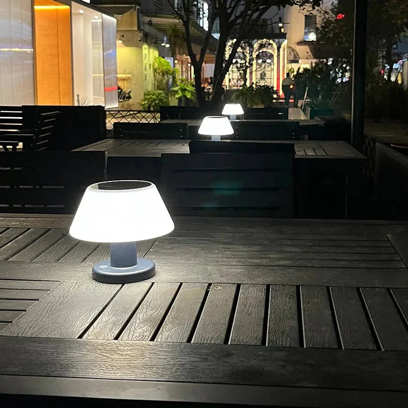 Moderne LED-Tischlampe auf dunklem Holztisch in nächtlichem Außenbereich, stilvolle Beleuchtung.