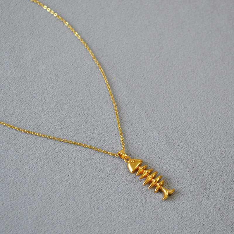 Goldene Fischgräten-Halskette auf grauem Hintergrund, eleganter Schmuck, modisches Accessoire.