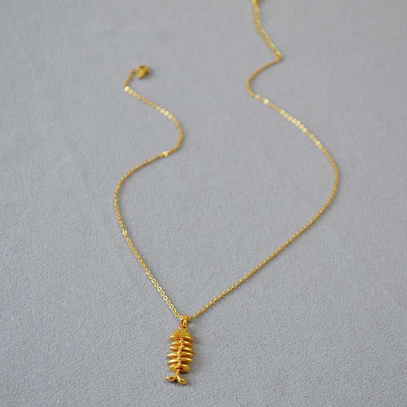 Goldene Halskette mit Fischgräten-Anhänger, eleganter Schmuck, modisches Accessoire.