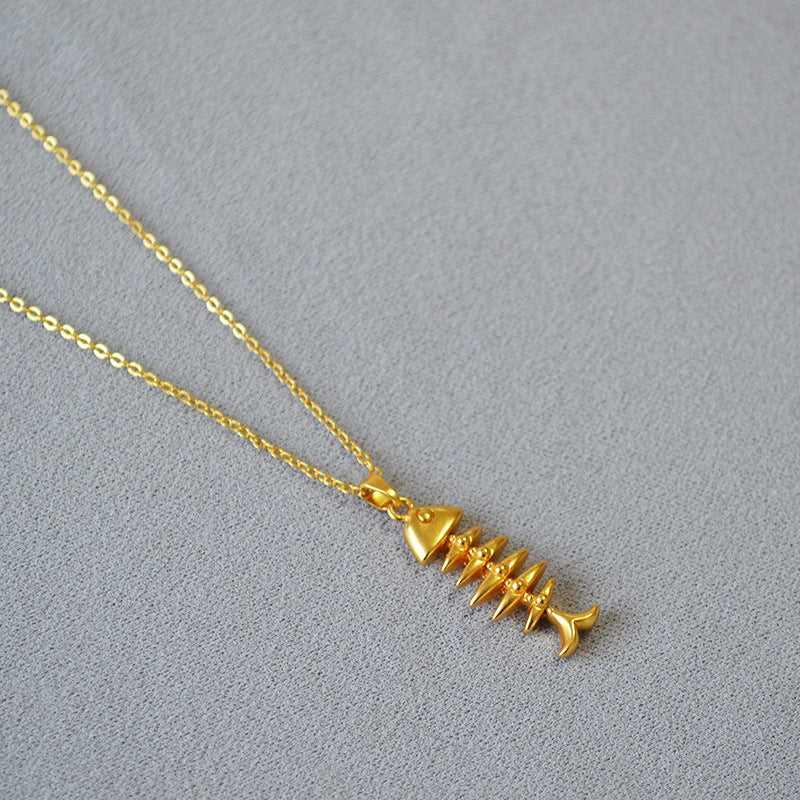 Goldene Fischgrätenkette auf grauem Hintergrund, eleganter Schmuck, modisches Accessoire.