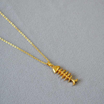 Goldene Fischgrätenkette auf grauem Hintergrund, eleganter Schmuck, modisches Accessoire.