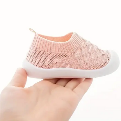 Rosa Babyschuh aus Strick mit weißer Sohle, handgehalten, bequem und atmungsaktiv.