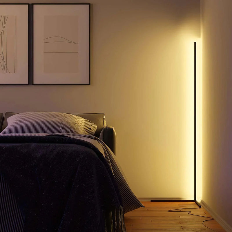 Schlanke Stehleuchte in der Zimmerecke taucht ein Schlafzimmer mit Bett und gerahmten Bildern in warmes Licht 4