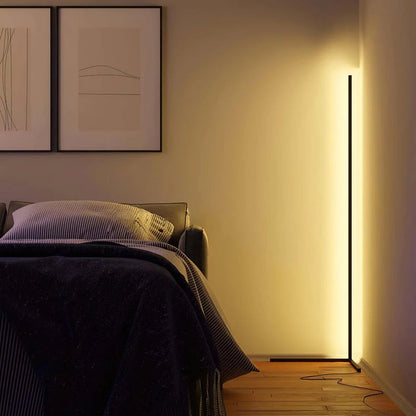 Schlanke Stehleuchte in der Zimmerecke taucht ein Schlafzimmer mit Bett und gerahmten Bildern in warmes Licht 4