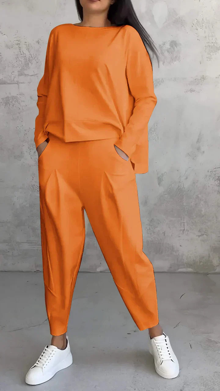 Frau in orangefarbenem Zweiteiler, lässiger Stil, weiße Sneaker, modische Damenbekleidung.
