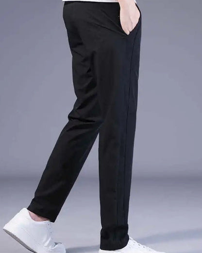 Schwarze Herren-Chinohose, schlank geschnitten, aus Baumwolle, mit weißen Sneakers.