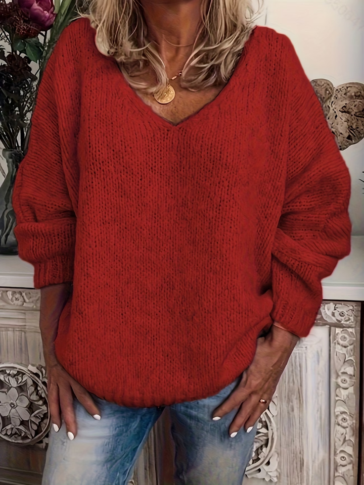 Grobstrickpullover in kräftigem Rot, getragen von einer Frau mit Jeans, die Hände an den Hüften, lockere Passform. 5