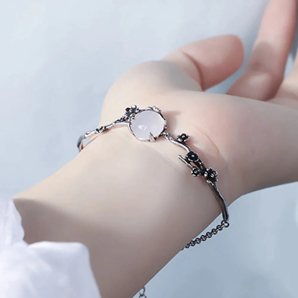 Silberarmband mit weißem Edelstein und Blumenmuster auf Hand, eleganter Schmuck für Damen.