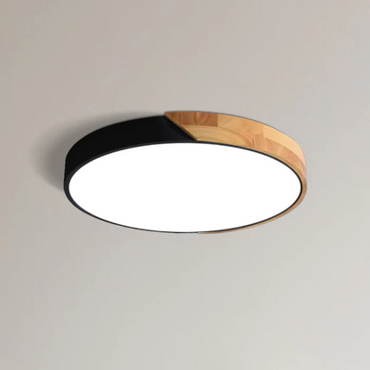 Schwarze flache Aufbauleuchte mit Holzsegment, freigestellt von schräg unten an einer hellen Decke 9