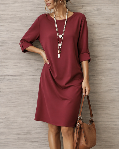 Weinrotes Kleid in Nahaufnahme, Model mit Herzketten und Schultertasche, Hand in der Hüfte, Ärmel mit Knopf hochgekrempelt 6