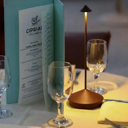 Tisch mit Weingläsern, Speisekarte und moderner Tischlampe in einem Restaurant.