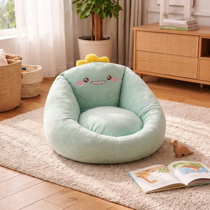 Mintgrüner Sitzsack als Dino mit gelbem Kamm und lächelndem Gesicht, daneben Buch und Holzdino 6