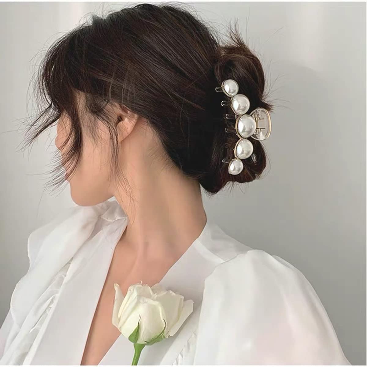 Frau mit Perlen-Haarklammer, Hochsteckfrisur, weiße Bluse, elegante Frisur, Modeaccessoire.