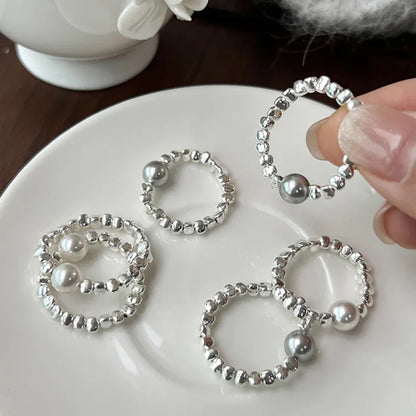Silberne Perlenringe auf Teller, handgefertigter Schmuck, elegantes Design, modische Accessoires.