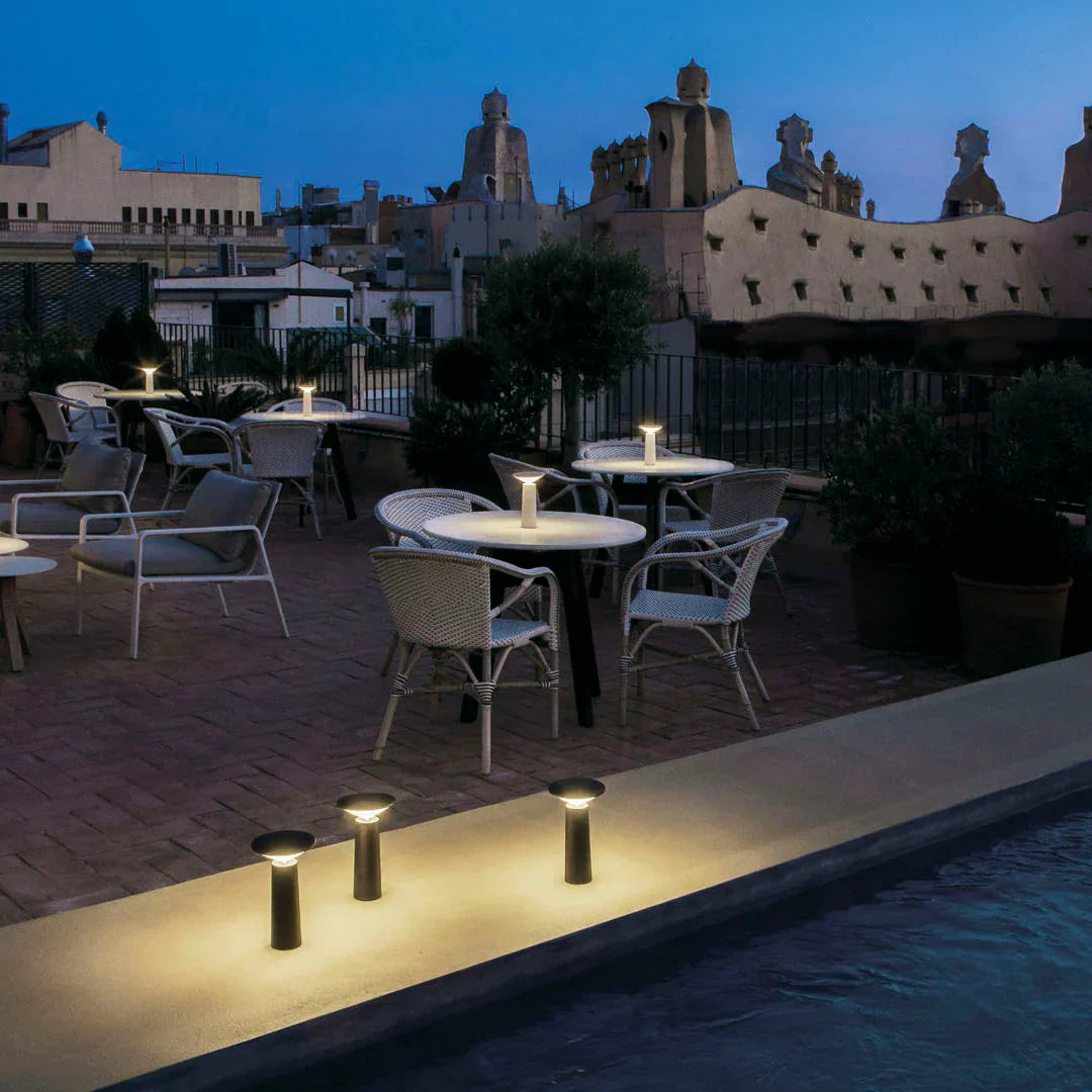 Terrassenbeleuchtung bei Nacht, moderne Außenleuchten, stilvolle Gartenmöbel, urbane Dachterrasse.