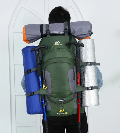 Mann mit grünem 60L Wanderrucksack, Isomatte, Zelt, Trekkingstöcke, Outdoor-Ausrüstung.
