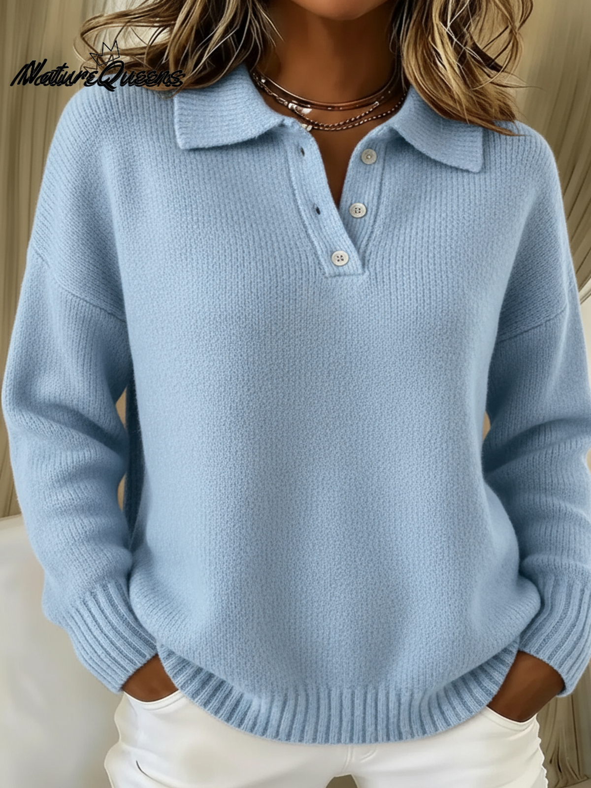 Hellblauer Strickpullover mit Polokragen und Knopfleiste, getragen von einer Frau mit weißer Hose, Hände in den Taschen. 1