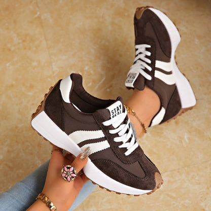 Dunkelbraune Sneaker mit weißen Streifen, ein Schuh in der Hand gehalten, der andere am Fuß 3