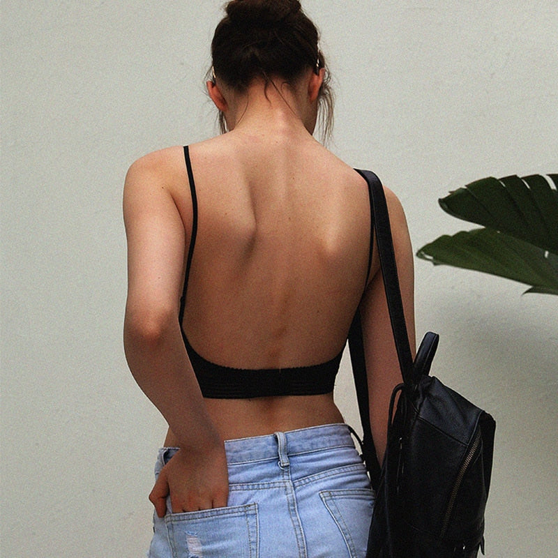 Rückansicht einer Frau im schwarzen BH mit sehr tiefem, offenem Rücken, dazu Jeansshorts und ein schwarzer Rucksack. 2