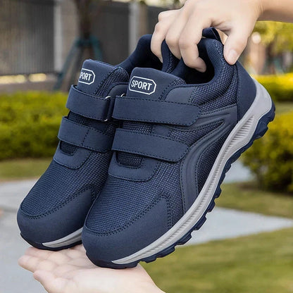 Hand hält ein Paar blaue Klettschuhe vor einer grünen Parkkulisse in die Höhe 12