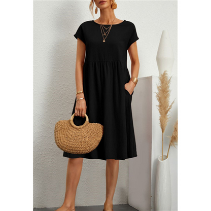 Frau in schwarzem Baumwollkleid, A-Linie, mit Strohtasche, Sommermode, Boho-Stil.