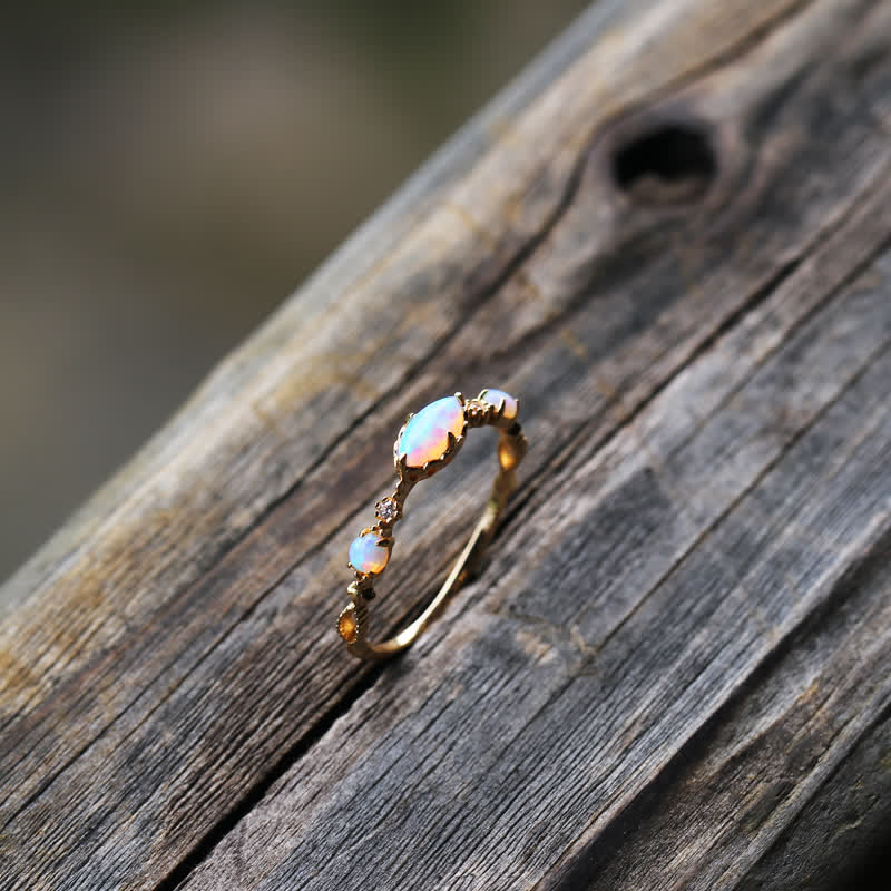 Opalring aus Gold mit drei Opalen auf Holz, eleganter Schmuck, Damenring, Geschenkidee.