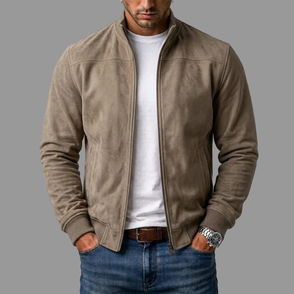 Mann trägt die graubeige Jacke in Wildlederoptik offen über weißem T-Shirt, Hände in den Jeanstaschen, Rippbündchen sichtbar. 2