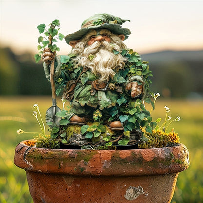 Gartenwichtel mit Hut, Bart und Efeublättern in einem alten Terrakottatopf vor verschwommener Abendwiese. 14