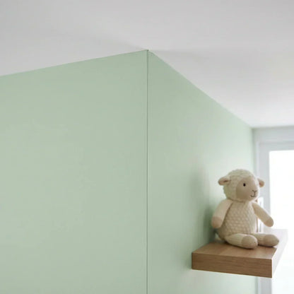Hellgrüne Zimmerecke mit sauberer, gerader Kante zur weißen Decke und einem Stofflamm auf einem Holzregal 5