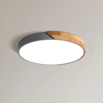 Graue flache Aufbauleuchte mit Holzsegment, freigestellt von schräg unten an einer hellen Decke 8