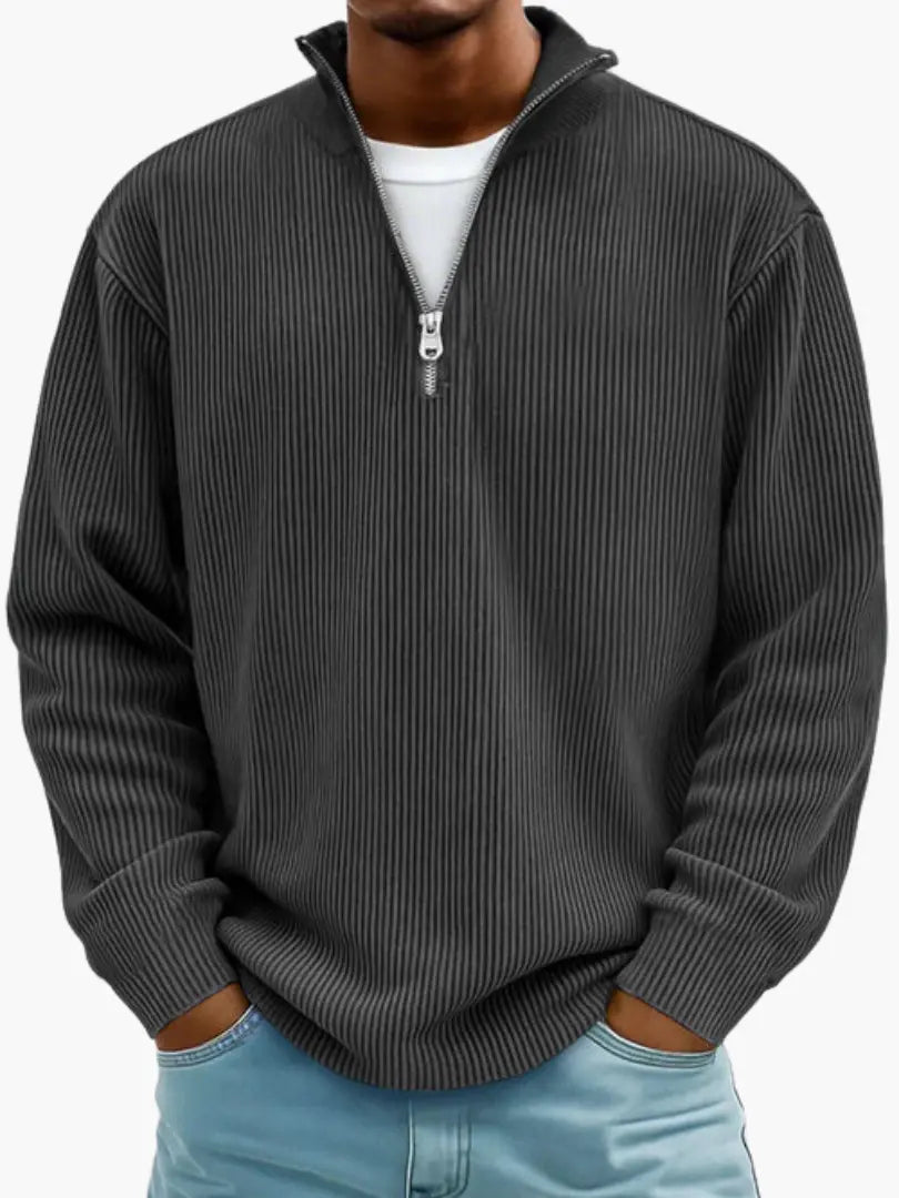 Vorderansicht des Rippstrick-Pullovers in Anthrazit mit silbernem Reißverschluss am Stehkragen, getragen mit hellblauer Jeans. 7