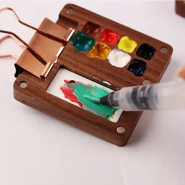 Mini-Aquarellkasten aus Holz mit Farbfächern und Pinsel, ideal für Künstler und Malerei.
