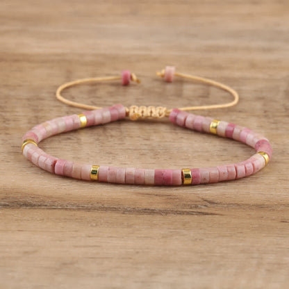 Rosa Perlenarmband mit goldenen Akzenten auf Holzoberfläche, handgefertigter Schmuck.