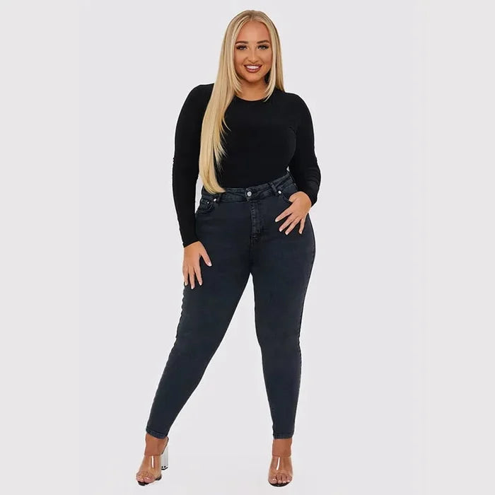 Frau in schwarzem Langarmshirt und dunkelblauer Jeans, Mode, Plus-Size, lächelnd, stehend.