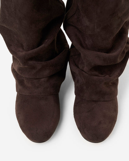 Draufsicht auf die Spitzen eines Paars dunkelbrauner Stiefel, die die runde Form und die Raffungen am Schaft zeigt. 5