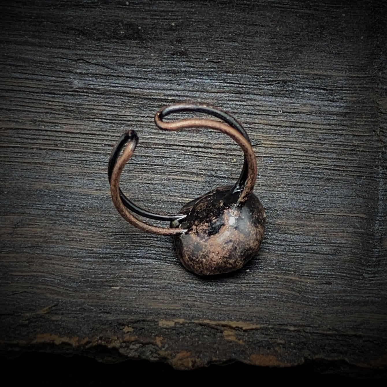Antiker bronzener Ring auf Holzoberfläche, rustikales Schmuckdesign, Vintage-Stil.