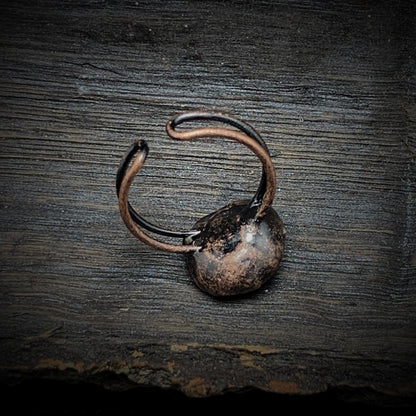 Antiker bronzener Ring auf Holzoberfläche, rustikales Schmuckdesign, Vintage-Stil.