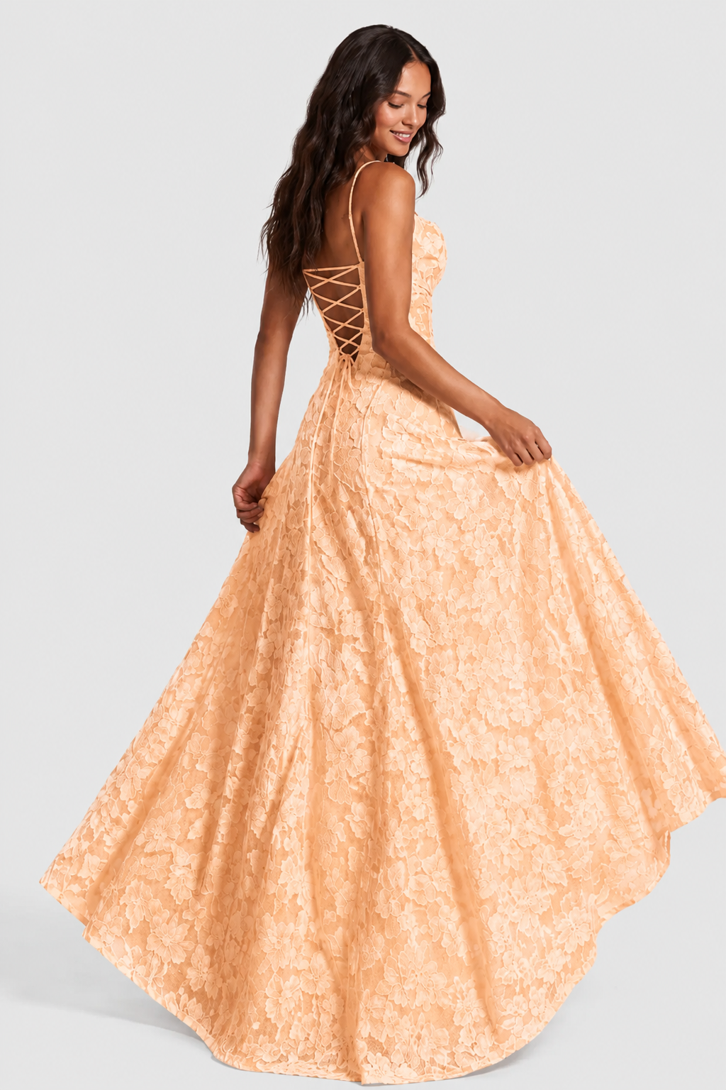 Pfirsichfarbenes Blumenspitzen-Kleid von hinten, Model dreht sich lächelnd und hält den Rock; geschnürter Rücken im Fokus. 15