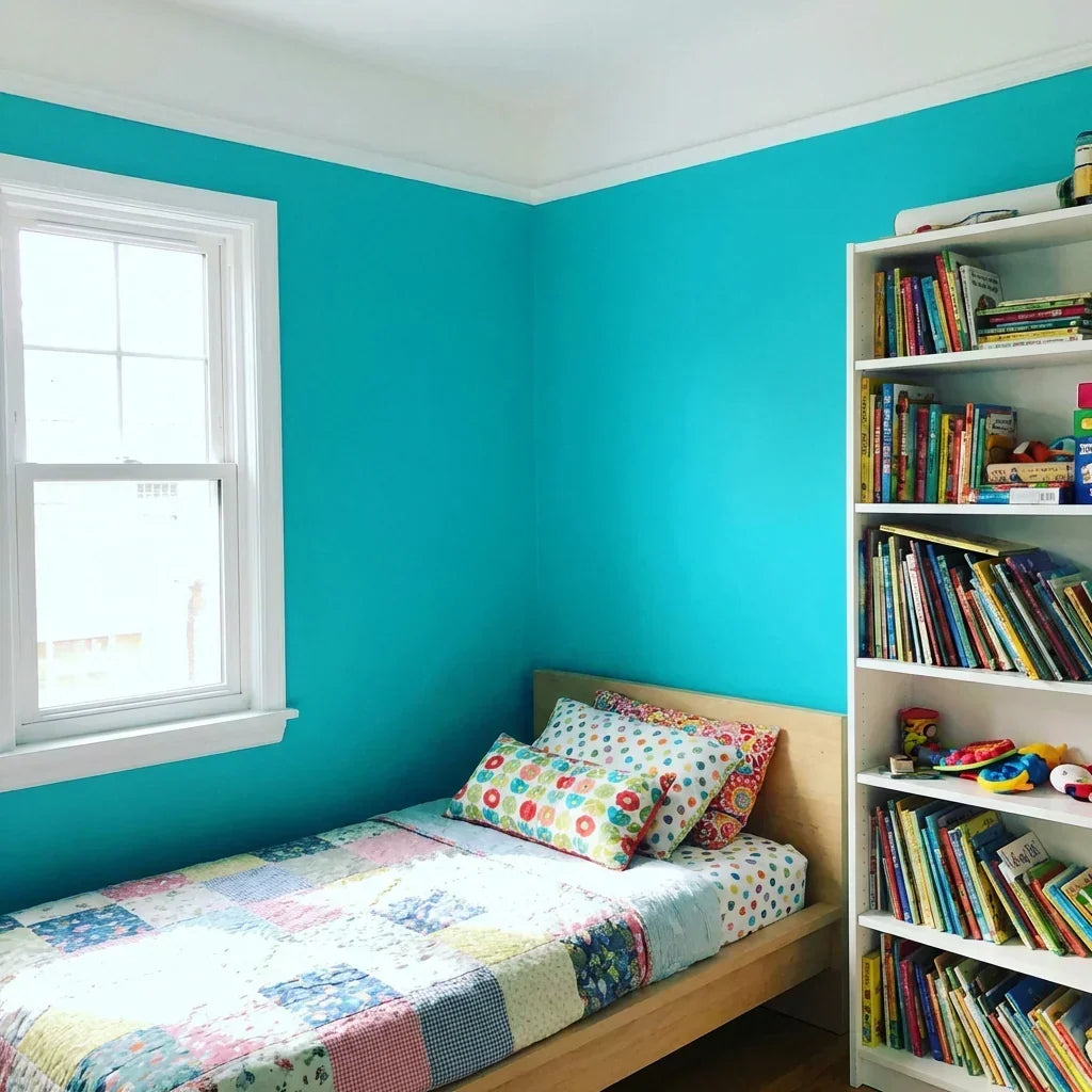 Kinderzimmer mit türkis gestrichenen Wänden, weißer Decke und Fensterrahmen, Bett mit Patchworkdecke und Bücherregal 9