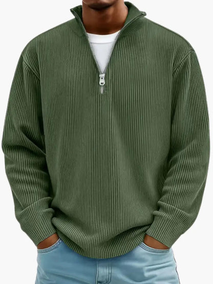 Model im gerippten Pullover mit Reißverschlusskragen in Olivgrün, lockere Passform, Hände in den Hosentaschen. 8