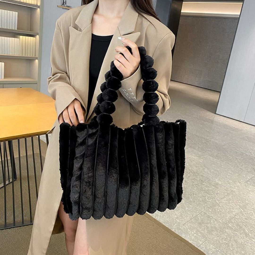 Frau mit schwarzer Plüsch-Handtasche, eleganter Mantel, modernes Büro, modisches Accessoire.