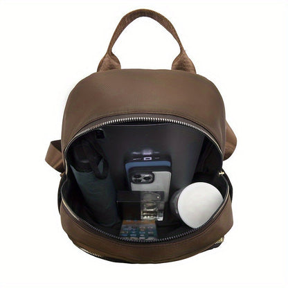 Geöffnetes Hauptfach des braunen Rucksacks, gefüllt mit Schirm, Smartphone, Parfümflasche und Dose 18