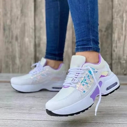 Frau trägt weiße Sneaker mit lila Akzenten, Jeans, Holzhintergrund, modische Damen-Sportschuhe.