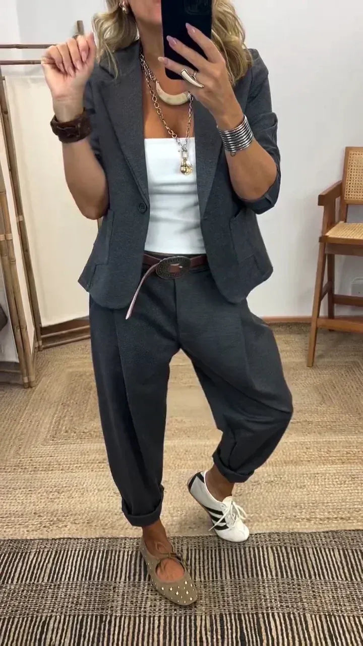 Frau im Spiegelselfie trägt das Set in Dunkelgrau mit Blazer, weißem Top, breitem Gürtel und aufgerollten Hosenbeinen. 1