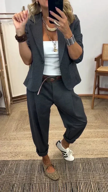 Frau im Spiegelselfie trägt das Set in Dunkelgrau mit Blazer, weißem Top, breitem Gürtel und aufgerollten Hosenbeinen. 1