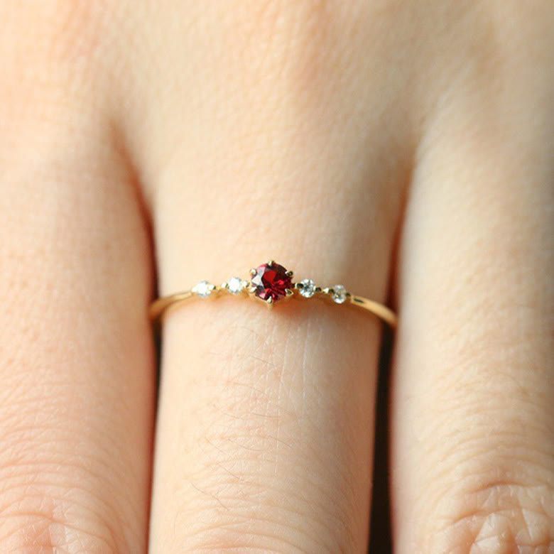 Dünner Goldring mit rotem Edelstein und kleinen Diamanten, eleganter Schmuck für Damen.